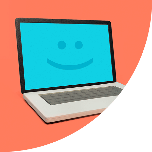 Ein weißer Laptop, auf dessen Screen ein Smiley zu sehen ist.