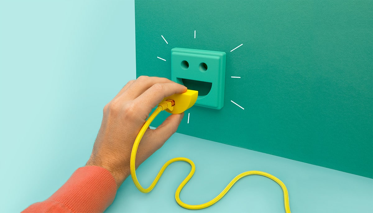 Eine Hand hält ein gelbes Kabel, das an eine grüne Wand angeschlossen ist.