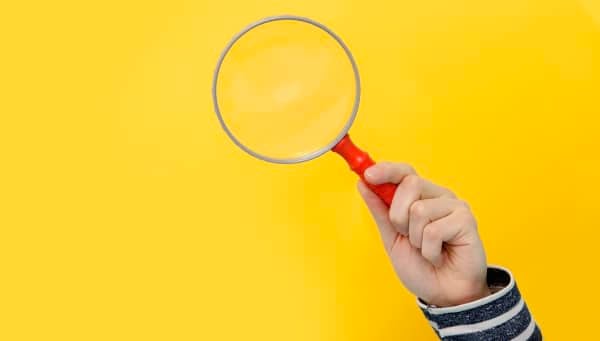 Hand holding a magnifying glass